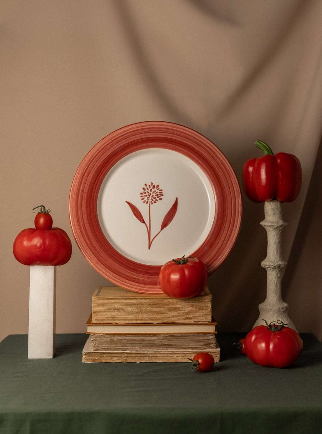 Cecilia Hand-Painted Ceramic Dinner Plate - Red and white - on top of the books